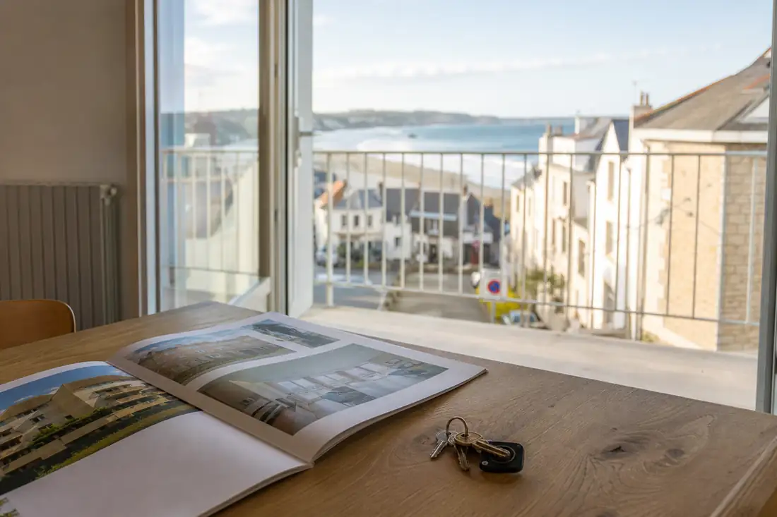 Balcon d’un appartement de petite station balnéaire avec clés et dossier de visite sur une table.