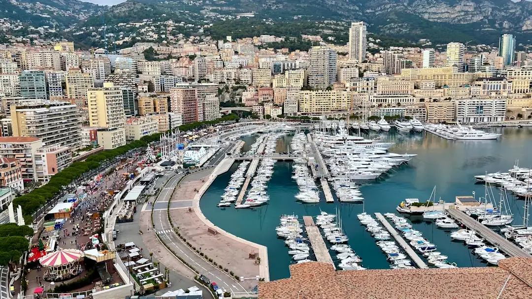 Dossier de transaction immobilière et plans consultés dans une agence à Monaco face à des immeubles résidentiels.