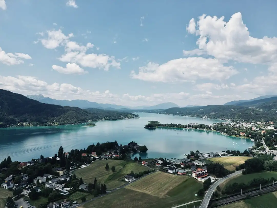 Immeuble résidentiel au bord du Wörthersee avec dossier immobilier et calculatrice sur un banc en premier plan.