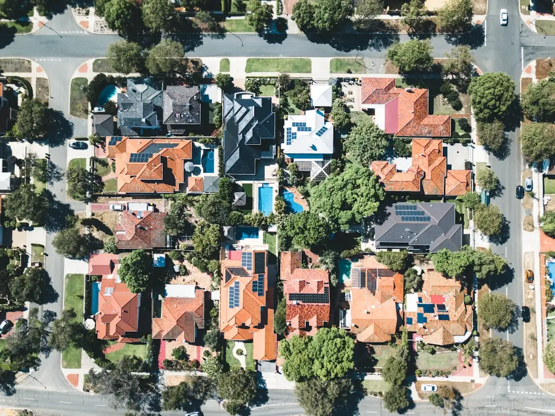 Deux dirigeants vus de dos examinent des maquettes immobilières dans un bureau face à un quartier d’affaires.