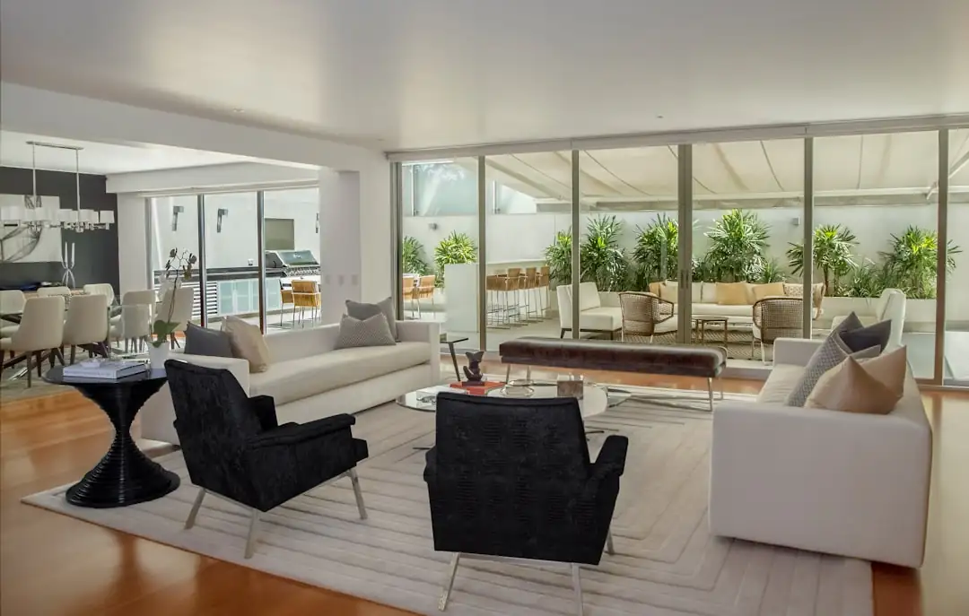 Couple et professionnel analysant des ventes comparables sur ordinateur dans un appartement lumineux.