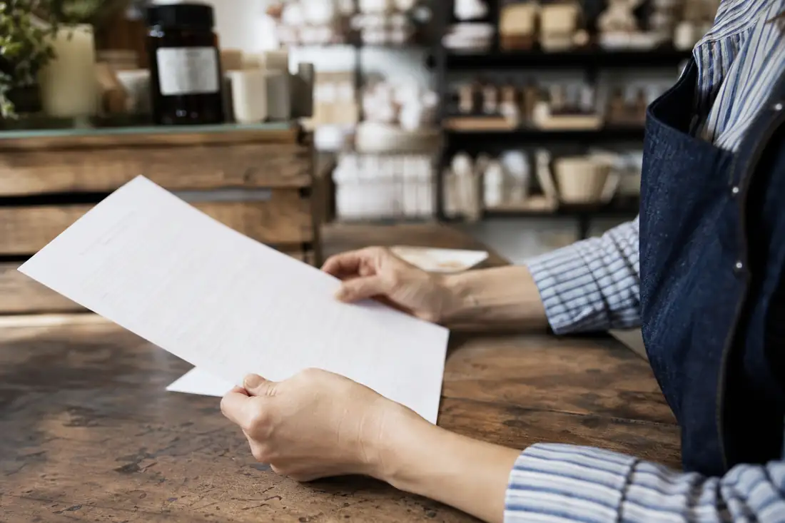 Commerçant consultant son contrat d'assurance multirisque professionnelle dans sa boutique