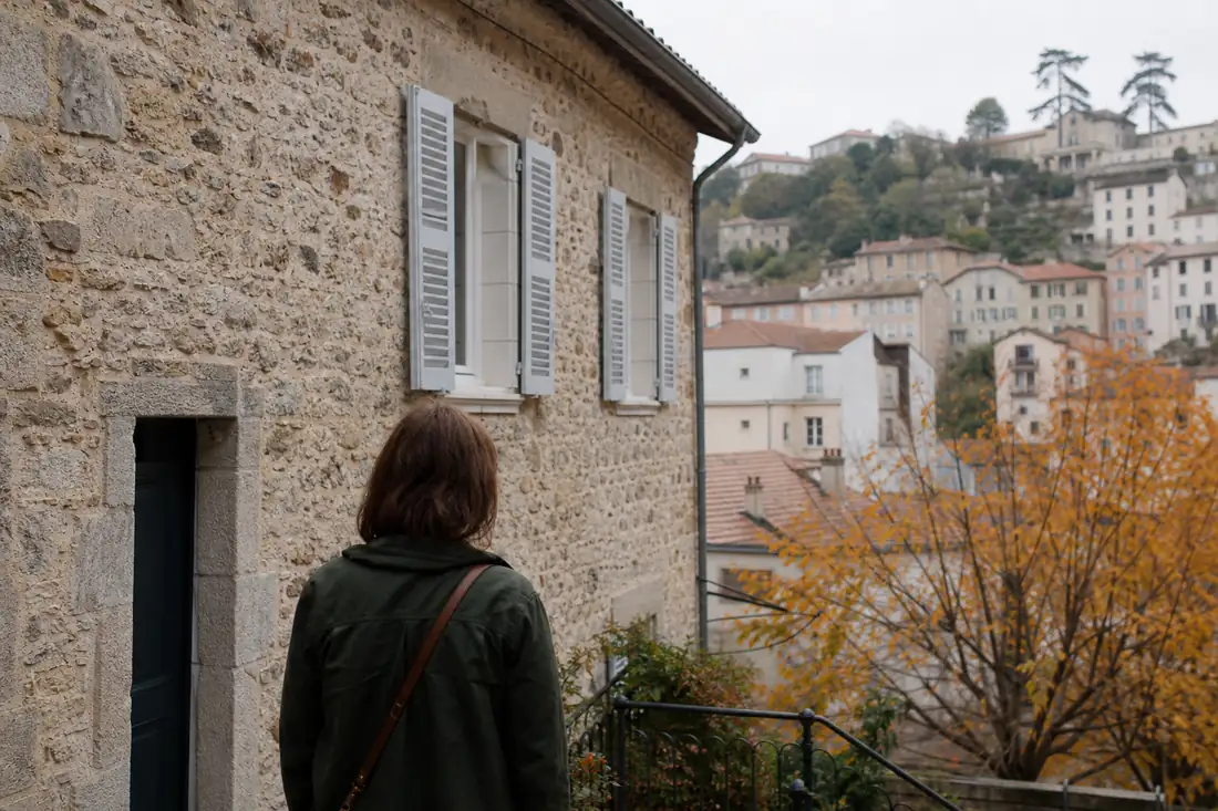 Acquéreur observant la façade d’un immeuble ancien dans un quartier résidentiel d’Auvergne-Rhône-Alpes.