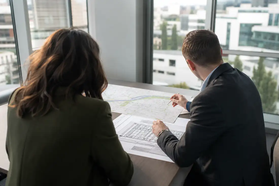 Deux conseillers consultent des plans d’immeubles dans un bureau régional dédié à l’immobilier commercial.