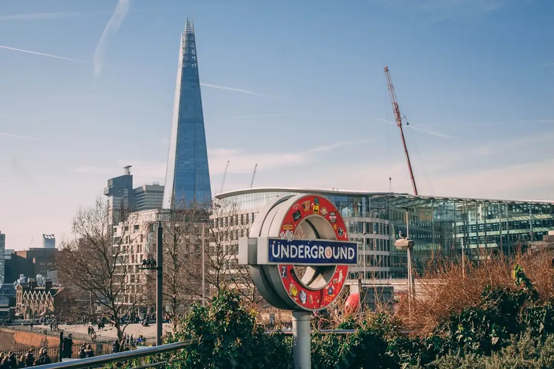Quartier d’affaires londonien avec immeubles de bureaux et investisseur consultant les marchés sur smartphone.