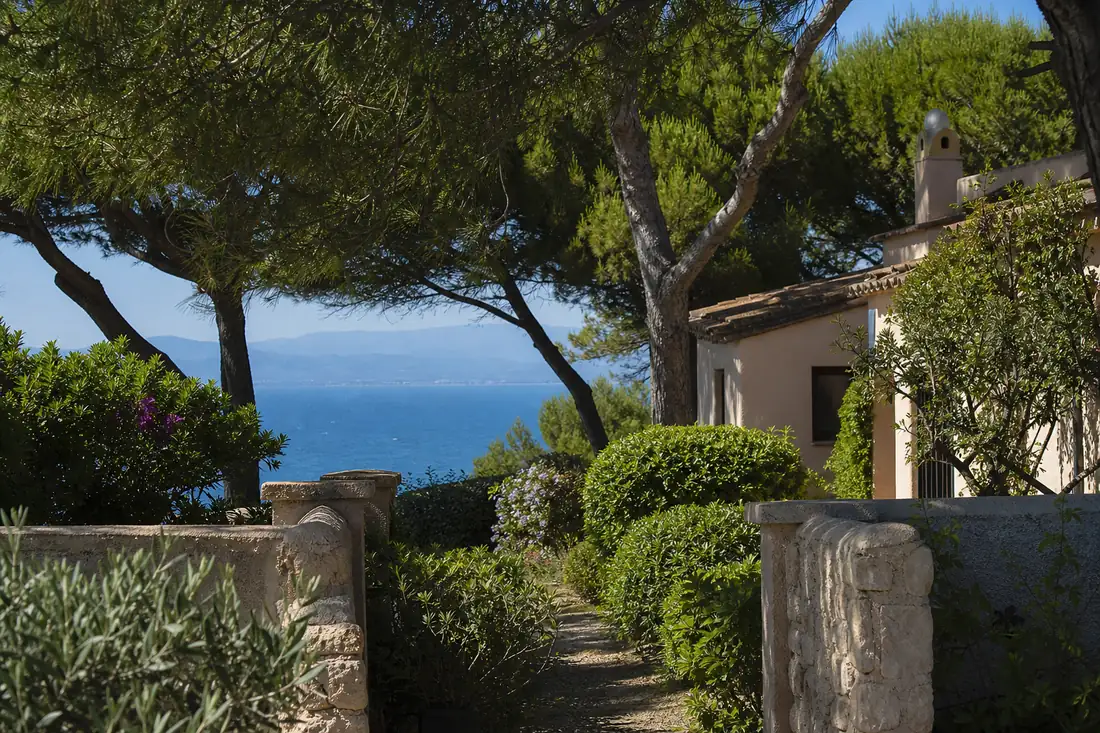 Villa méditerranéenne discrète derrière une végétation dense, près du littoral de Saint-Tropez.