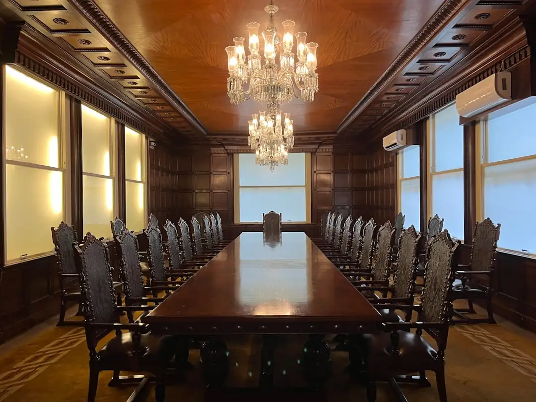 Salle de conseil vitrée avec dossiers immobiliers et immeubles résidentiels urbains visibles en arrière-plan.