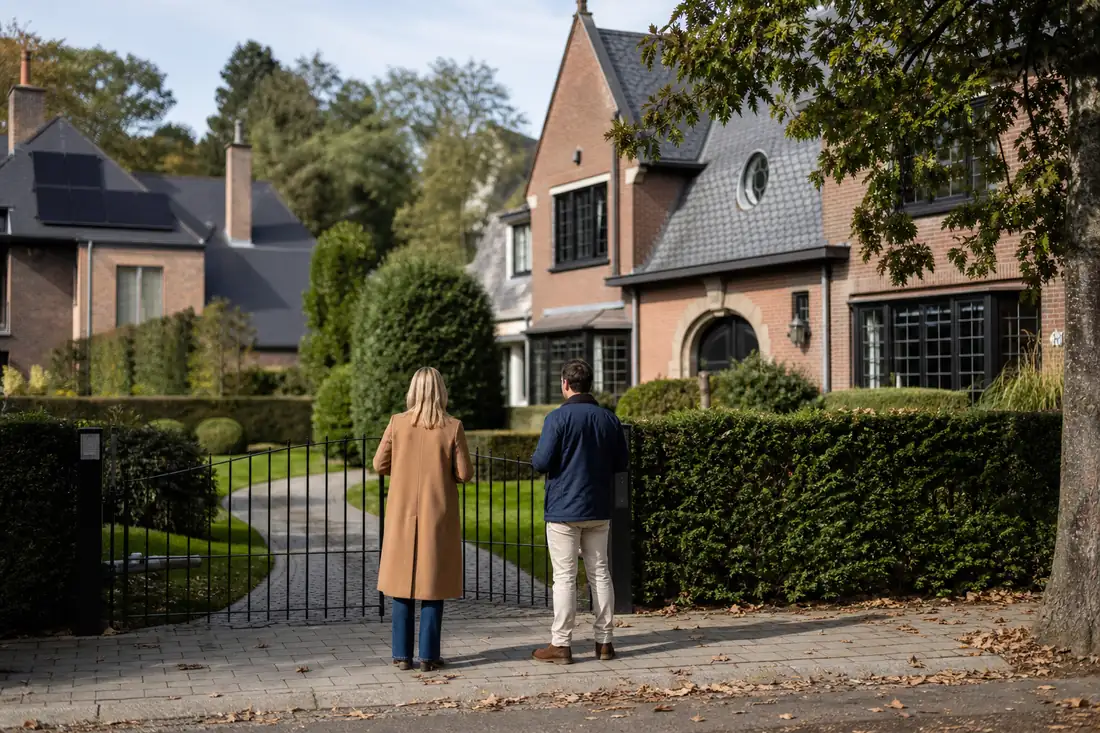 Façades résidentielles arborées à Waterloo, devant une maison familiale en brique et pierre en Belgique.