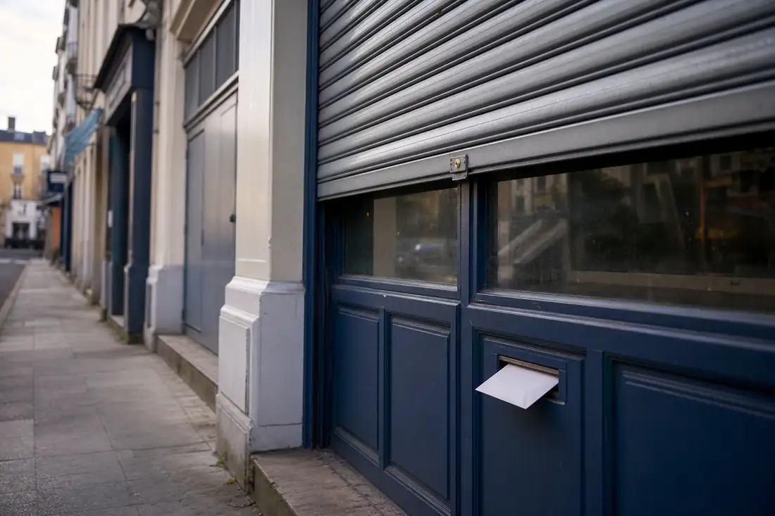 Devanture d’un commerce fermé avec un pli officiel glissé dans la boîte aux lettres