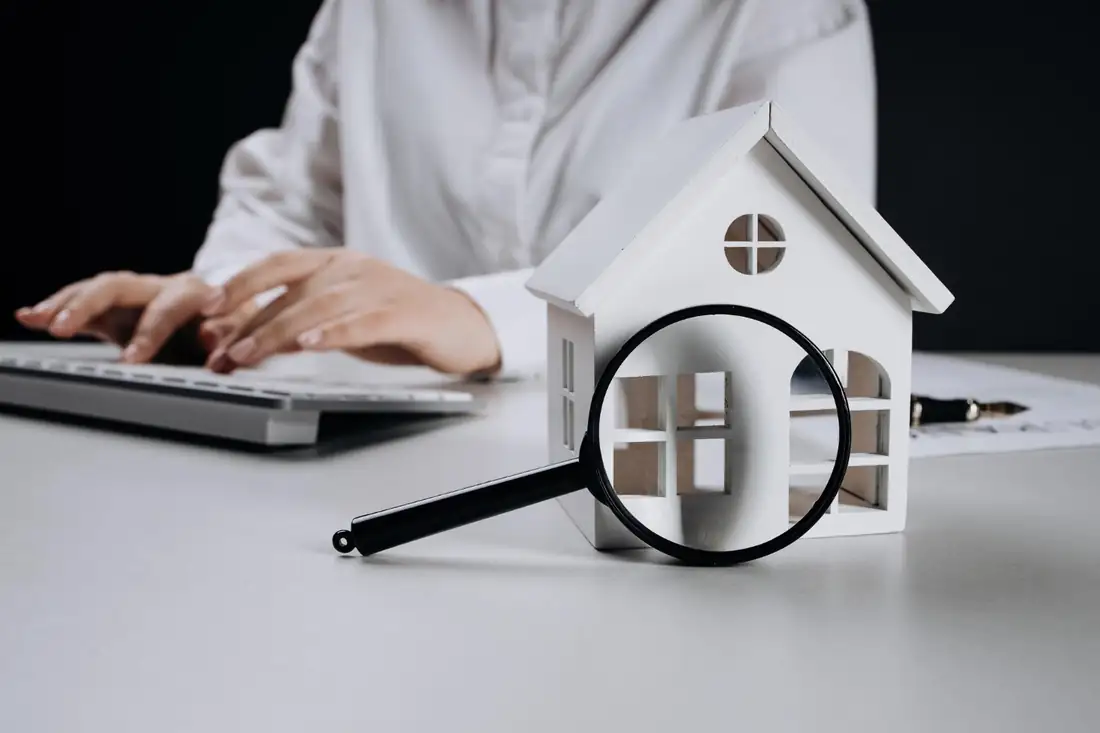 Dossier immobilier, plans et calculatrice sur une table lors d’un rendez-vous de gestion patrimoniale.