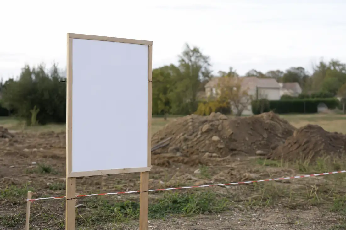 Panneau d'affichage du permis de construire installé sur un terrain à bâtir