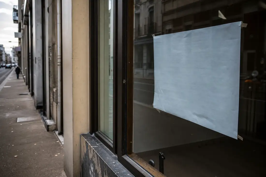 Vitrine de local commercial avec un avis de fin de bail affiché en devanture