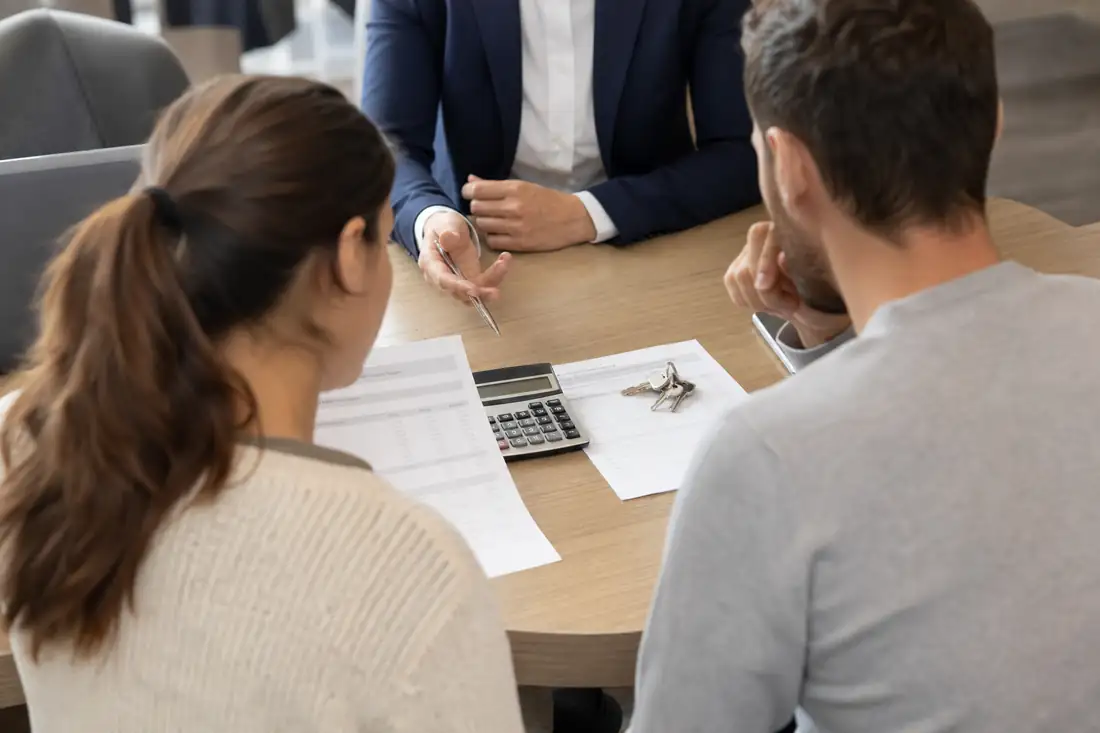 Un couple examine une offre de prêt immobilier et ses mensualités avec un conseiller bancaire en agence.