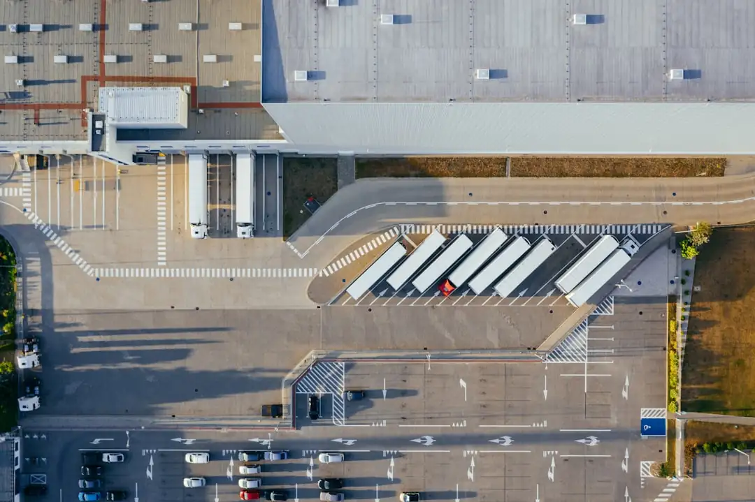Entrepôt logistique moderne avec quais de chargement et remorques dans une zone d’activités française.