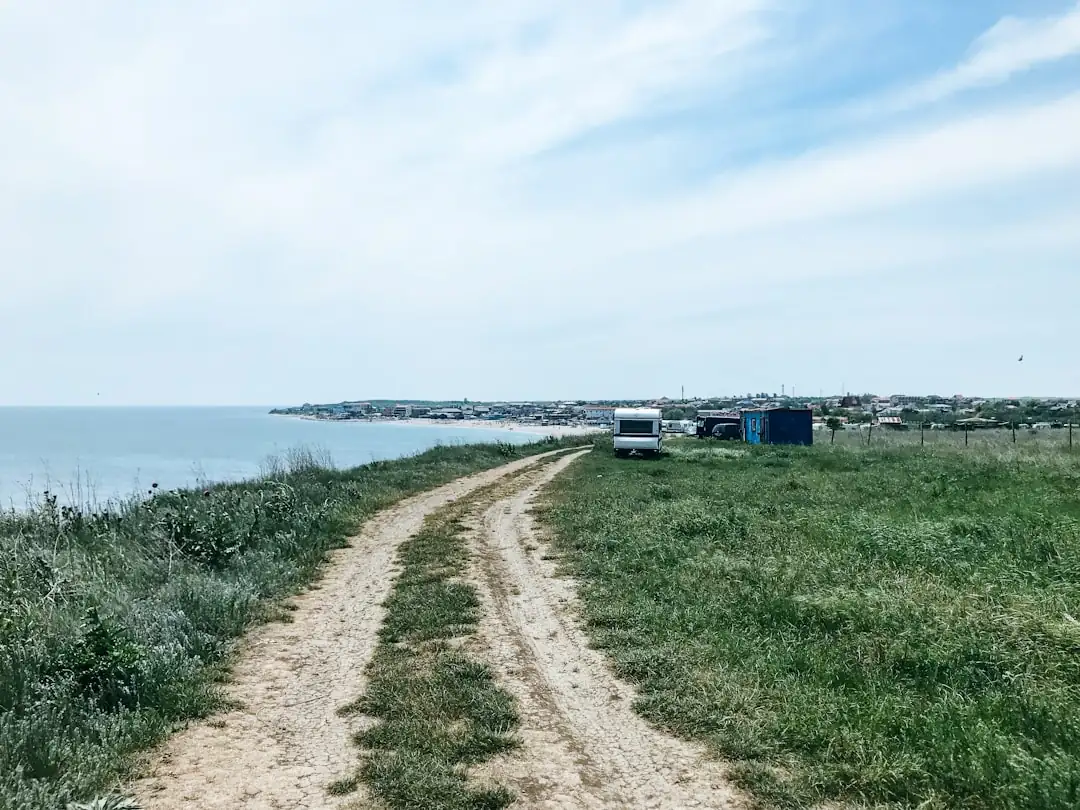 Fouille archéologique sur un terrain d’aménagement avec tranchées, structures au sol et engin de chantier en retrait.
