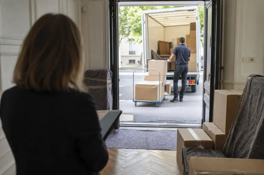 Cartons et matériel de déménagement dans l’entrée d’un immeuble résidentiel lors d’une vente immobilière.