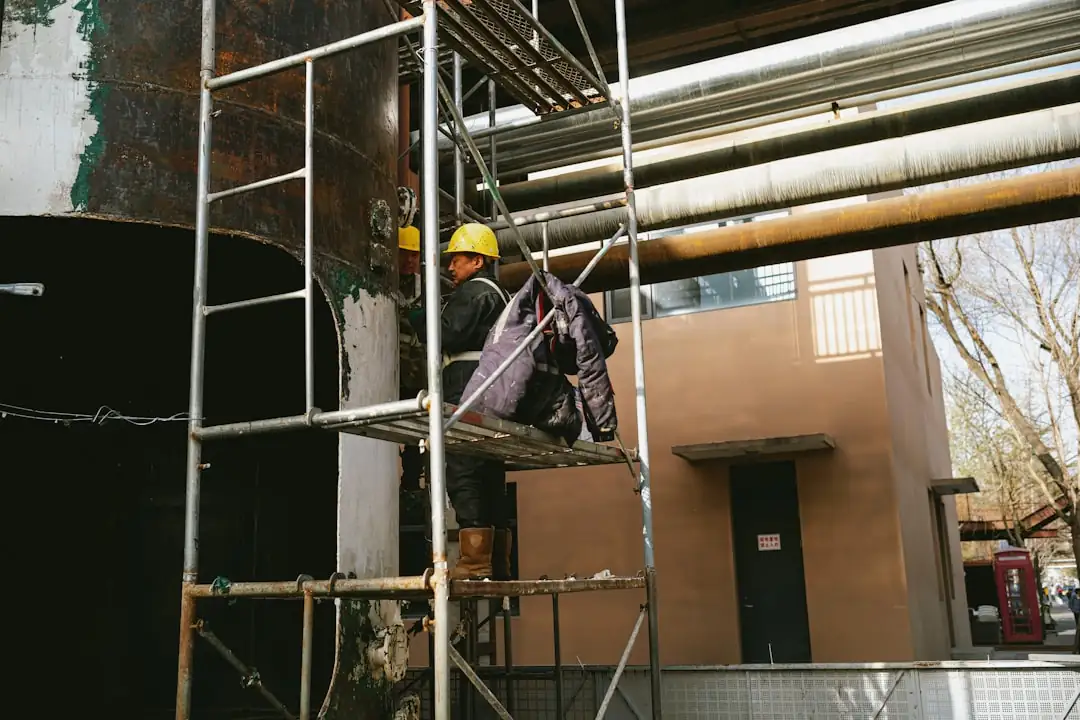 Réunion de chantier dans un immeuble en construction avec plans techniques et structure de béton visible au fond.