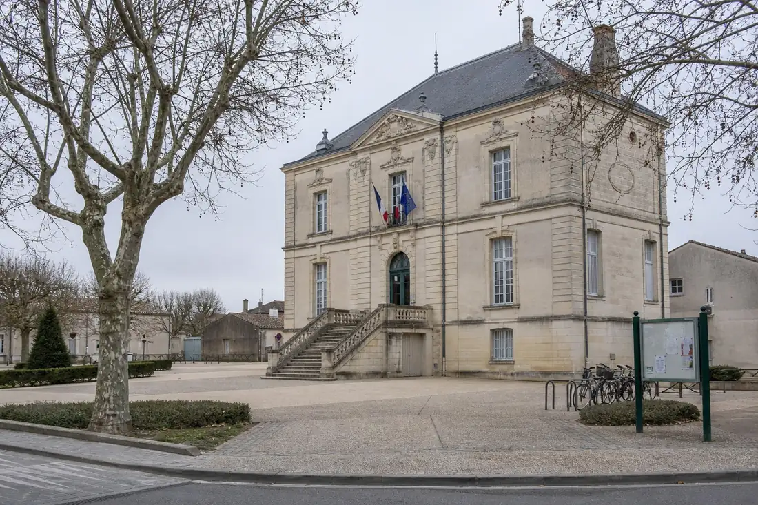 Façade en pierre d’une mairie de commune moyenne, escalier et panneaux d’affichage municipal un matin gris