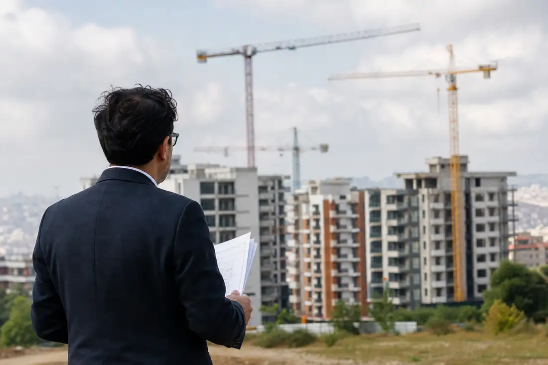 Investisseur examinant des documents devant un programme résidentiel en construction à Istanbul.