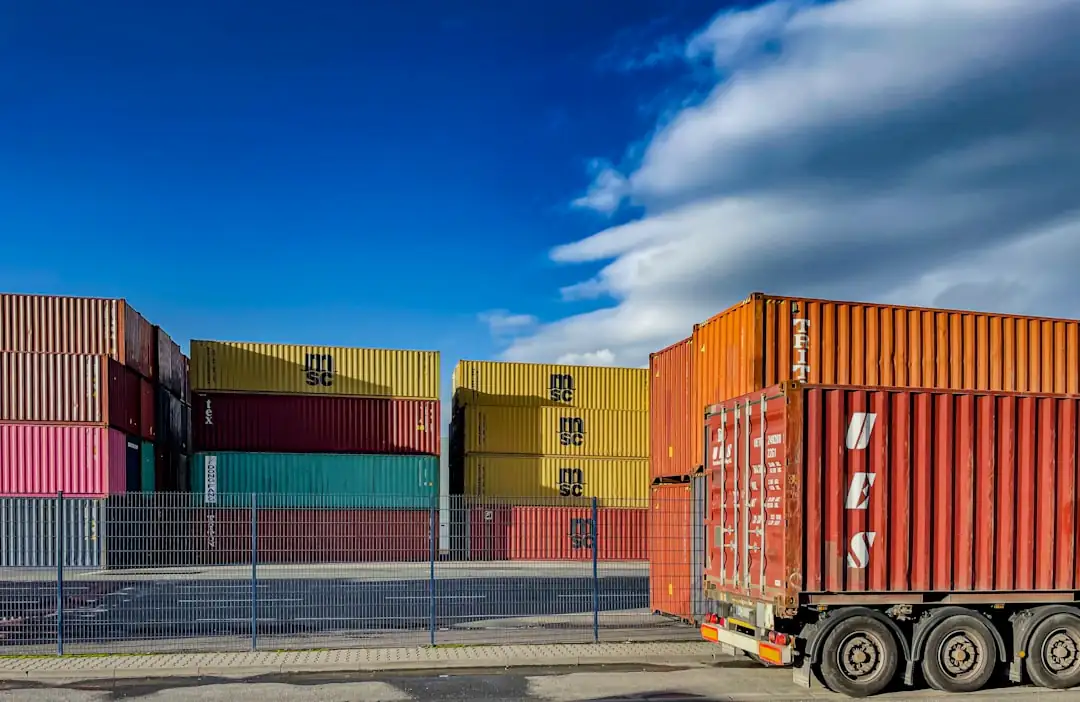 Entrepôts logistiques modernes alignés près d’un axe routier européen avec quais de chargement et camions non marqués.
