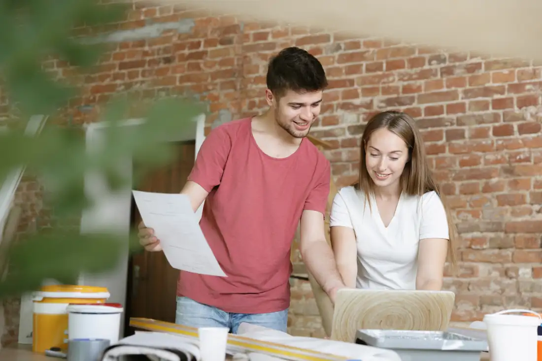 Propriétaire examinant plans, mètre et documents pour estimer la valeur de sa maison et de son terrain.