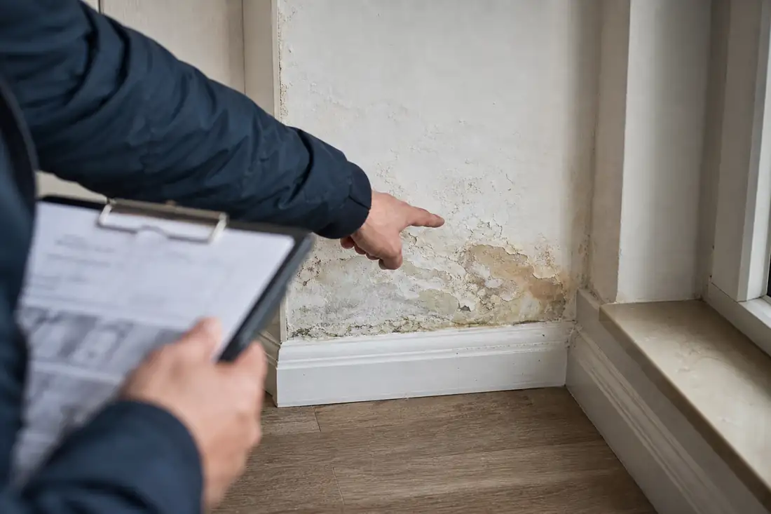 Expert examinant des dégâts des eaux dans un logement lors d'une visite d'expertise assurance
