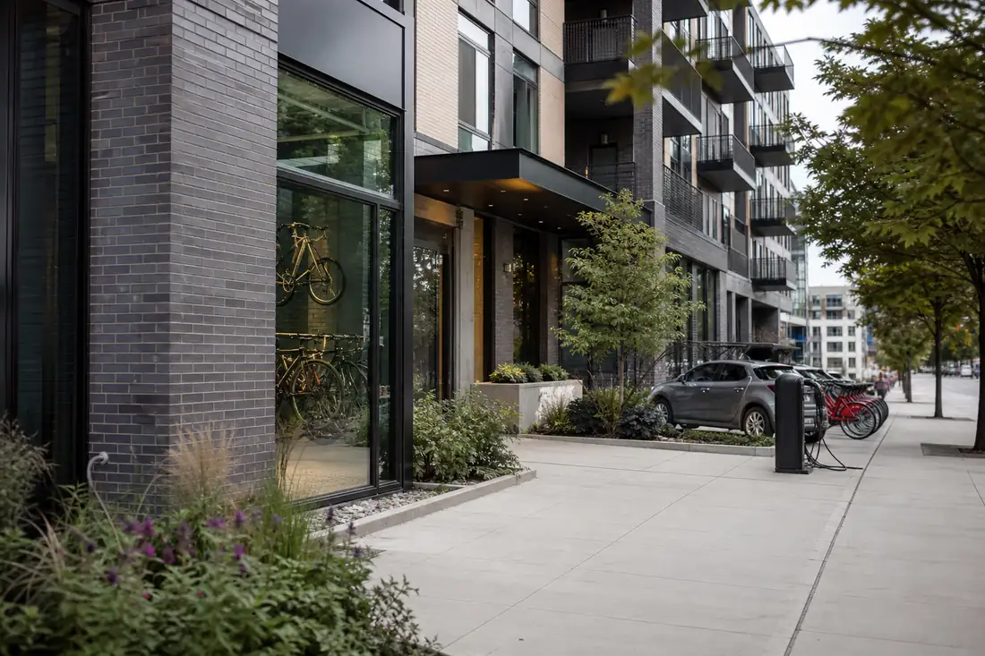 Immeuble résidentiel américain contemporain avec local vélos, bornes de recharge et trottoirs paysagers.