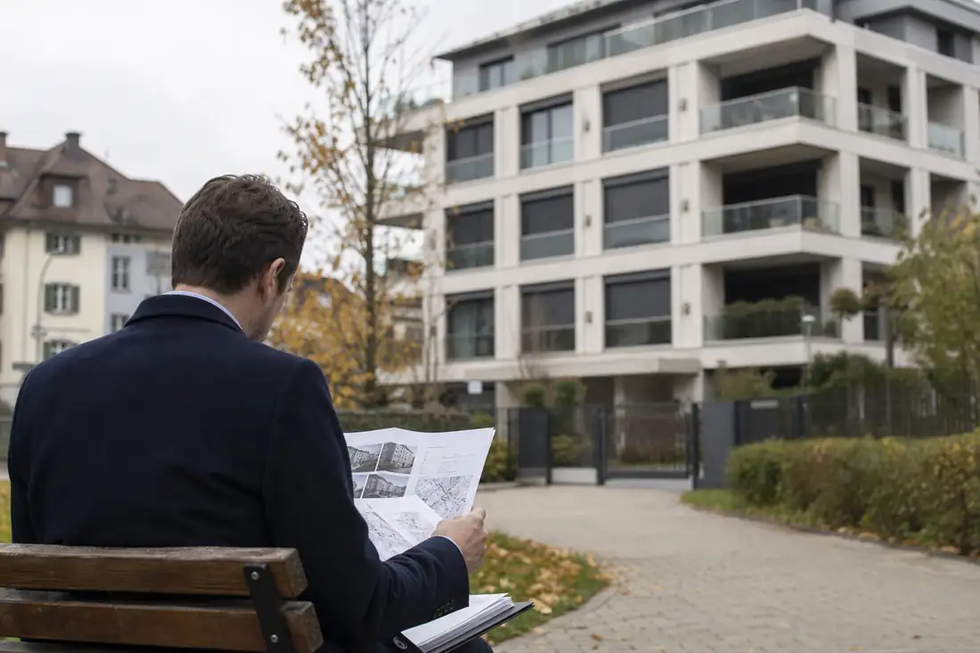 Immeuble résidentiel suisse et documents financiers consultés par un investisseur, vus sans visage identifiable.
