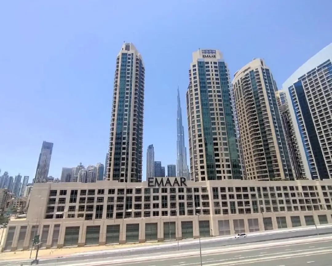 Investisseur consultant un dossier d’achat dans un appartement contemporain face au skyline de Dubaï.