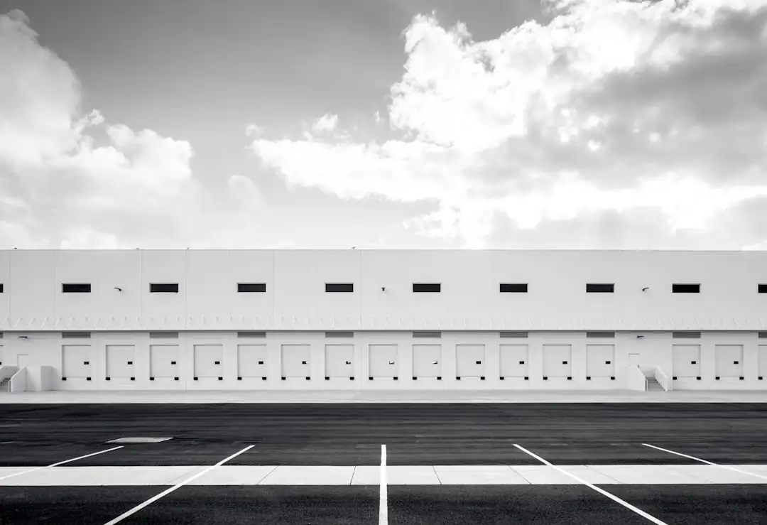 Entrepôt logistique moderne et documents financiers consultés par un investisseur sur un bureau.