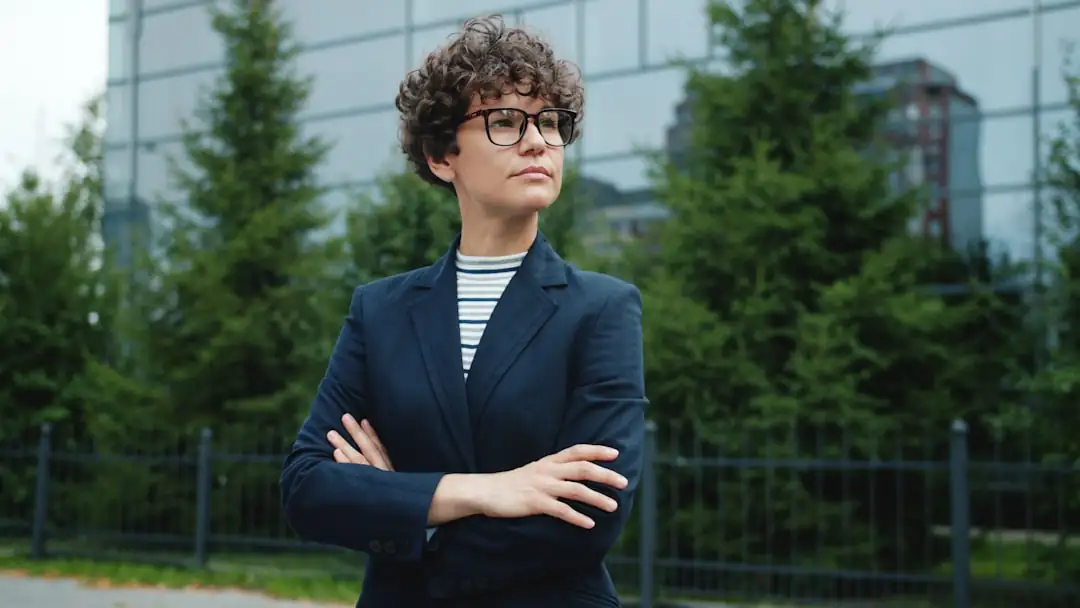 Dirigeant vu de dos examinant des plans d’immeuble tertiaire dans un bureau donnant sur un quartier d’affaires.