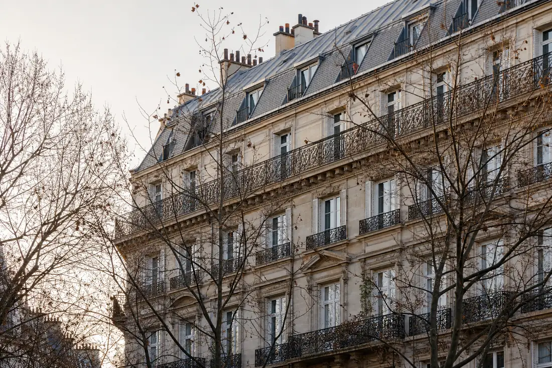 Façade d’immeuble haussmannien en pierre de taille, balcons en fer forgé et toiture en zinc