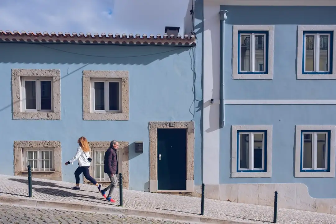 Investisseur examinant les documents d’un appartement portugais depuis une terrasse avec vue urbaine littorale.