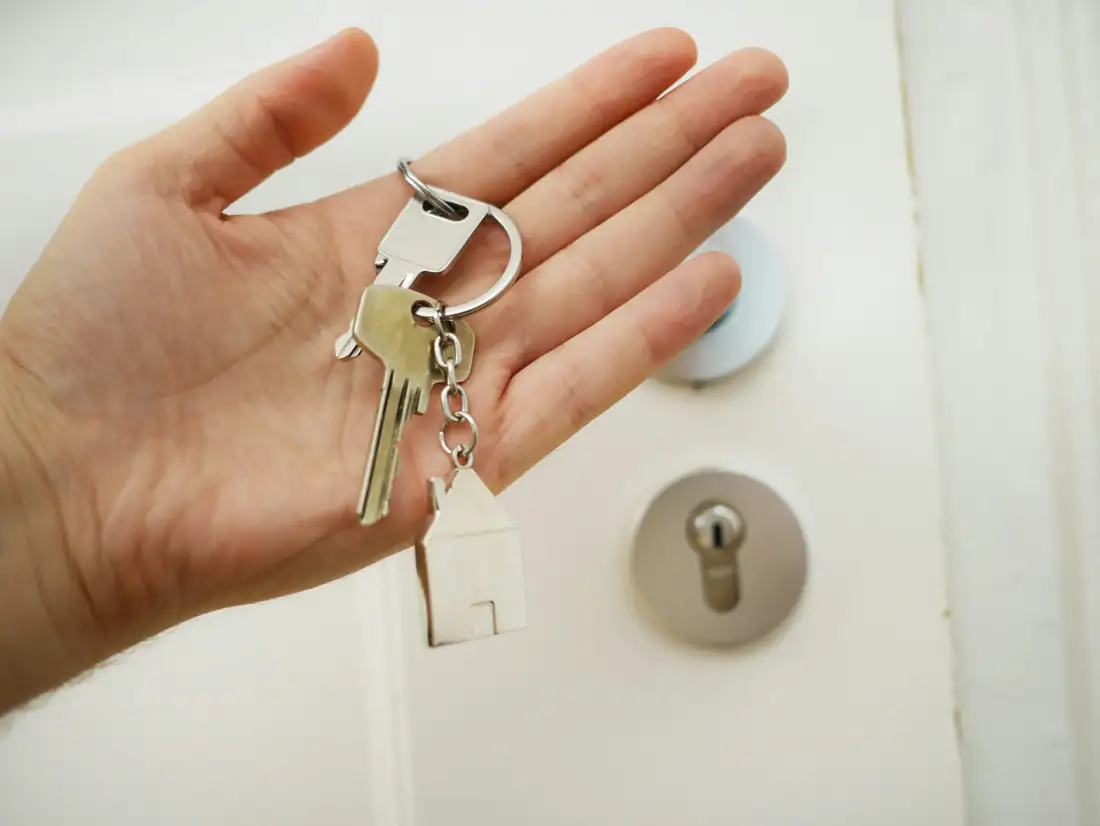 Couple observant des annonces immobilières floues devant une agence dans un quartier résidentiel français.