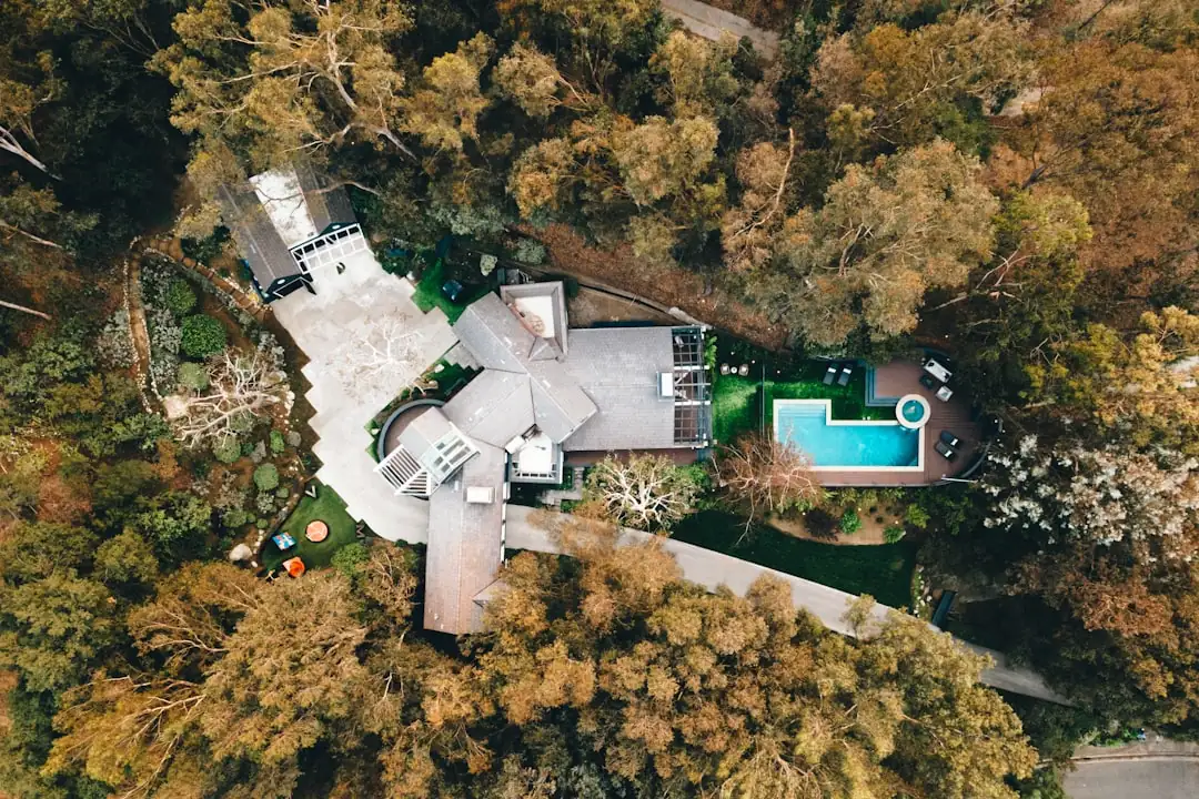 Demeure en pierre entourée d’arbres avec un dossier notarial posé au premier plan, symbole de transmission immobilière.