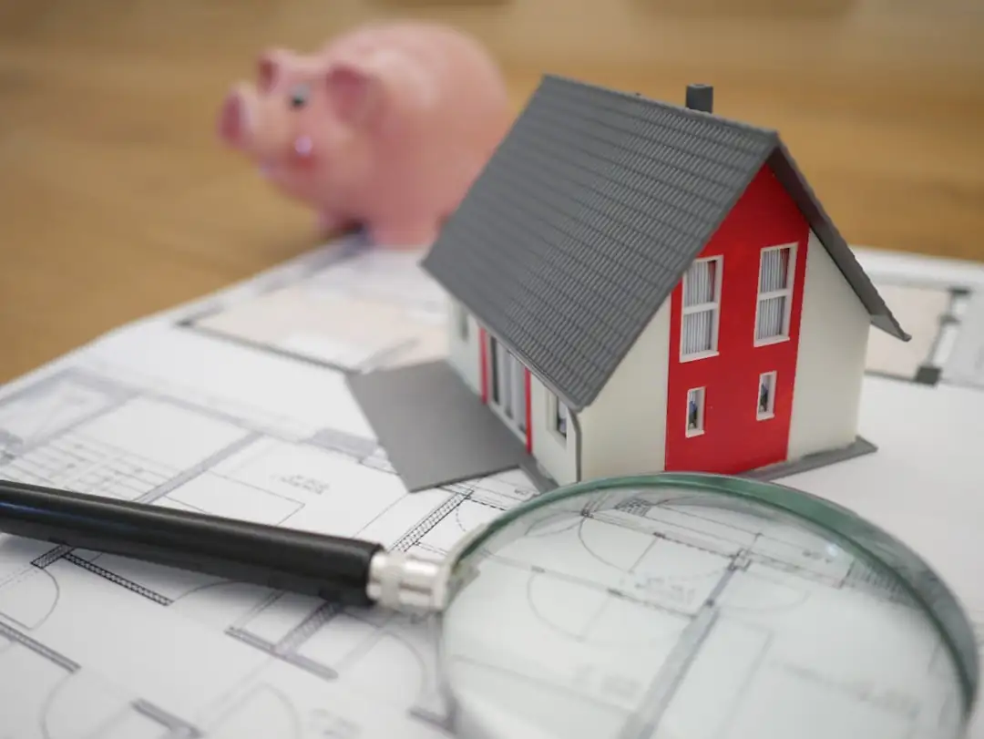 Dossier de financement et plans non lisibles devant des immeubles résidentiels en construction à l’arrière-plan.