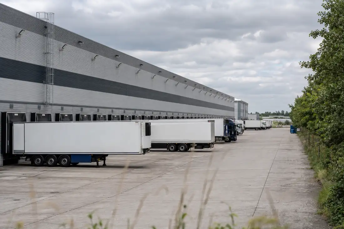 Grand entrepôt logistique avec quais de chargement et cour poids lourds dans une zone d’activité près de Compiègne.