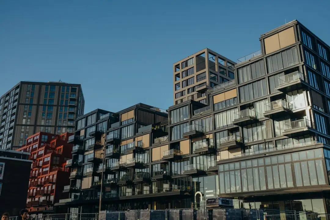 Maisons mitoyennes belges, dont une en rénovation énergétique, observées par des acquéreurs de dos.