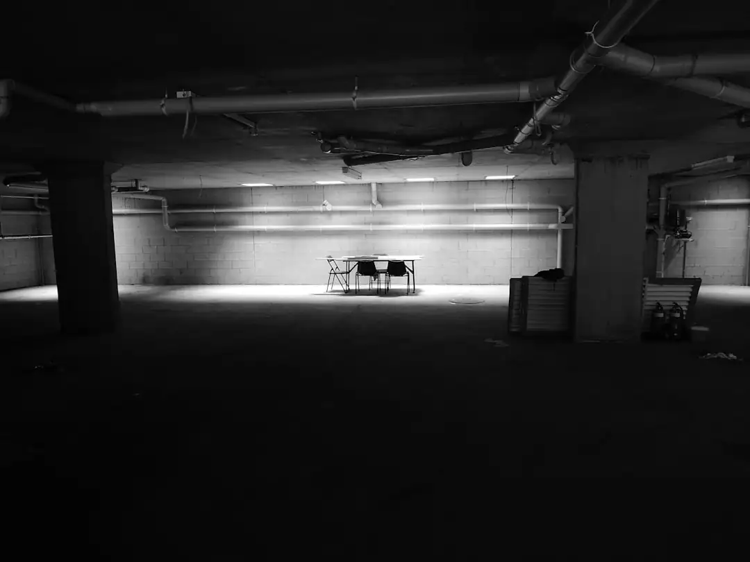 Emplacement de stationnement en sous-sol d’une résidence récente, près d’un dispositif de recharge électrique.