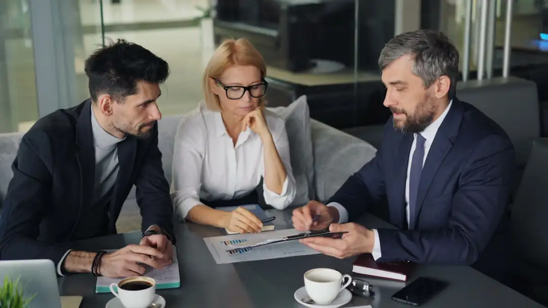 Réunion de travail autour de dossiers de financement immobilier dans une salle de conseil bancaire.