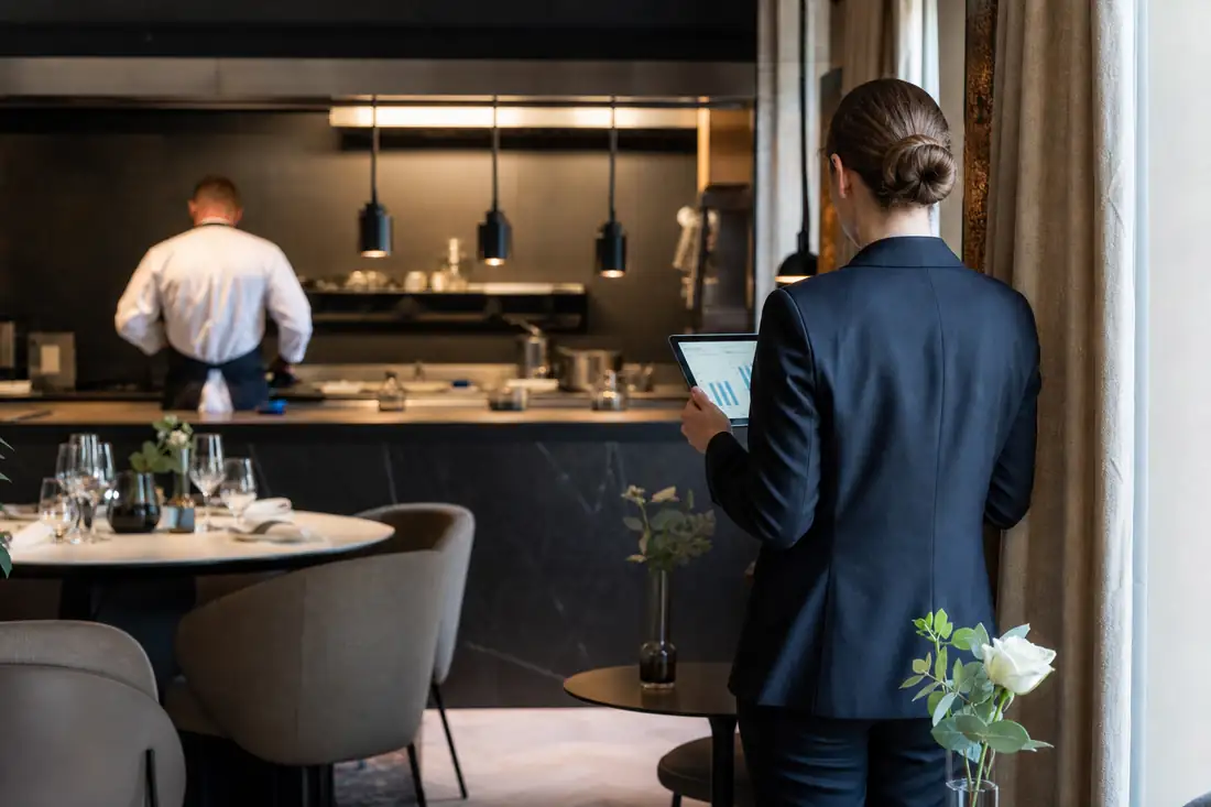 Restaurant d’hôtel contemporain avec cuisine ouverte et gestionnaire consultant des données d’exploitation.