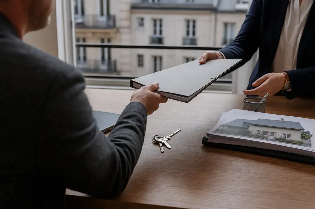 Dossiers de vente et clés sur un bureau d’agence lors de la transmission d’un portefeuille immobilier.