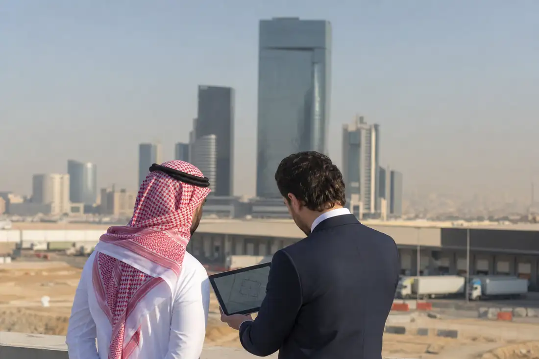 Quartier d’affaires saoudien avec immeubles de bureaux modernes et professionnels examinant un projet immobilier.