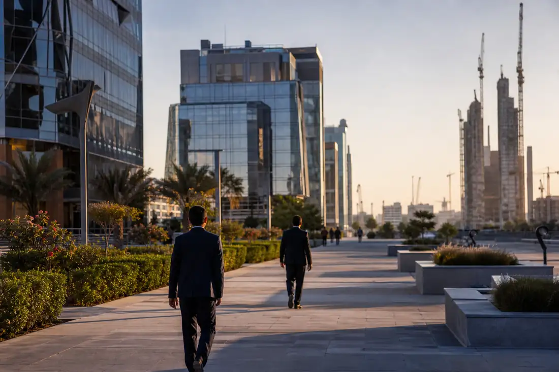 Quartier d’affaires moderne de Riyad avec tours de bureaux, chantier urbain et allées paysagères au matin.