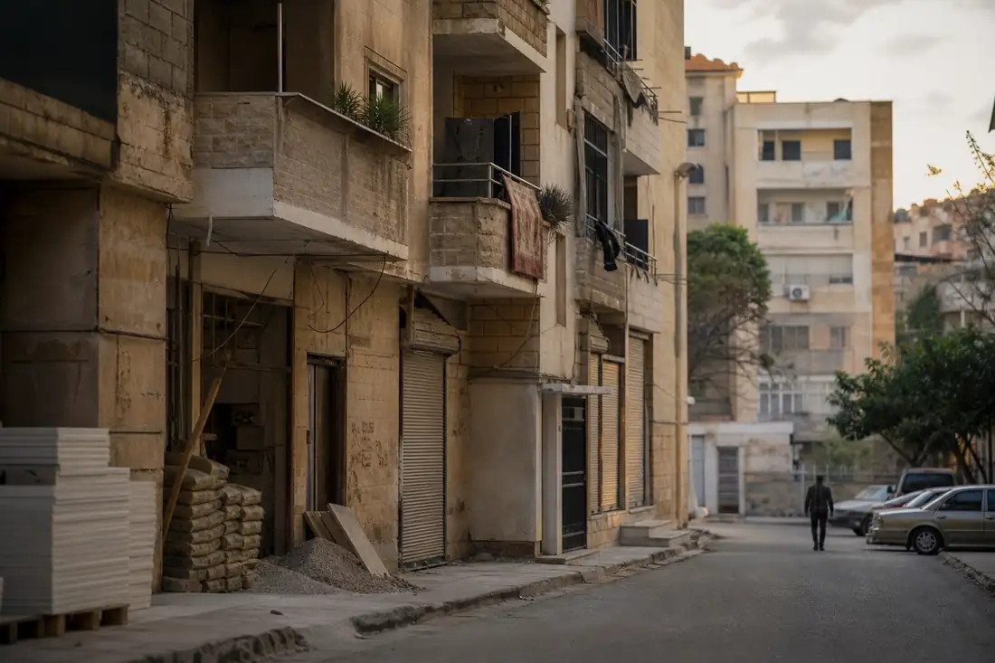 Immeuble résidentiel partiellement rénové dans un quartier urbain syrien, avec matériaux de chantier au sol.