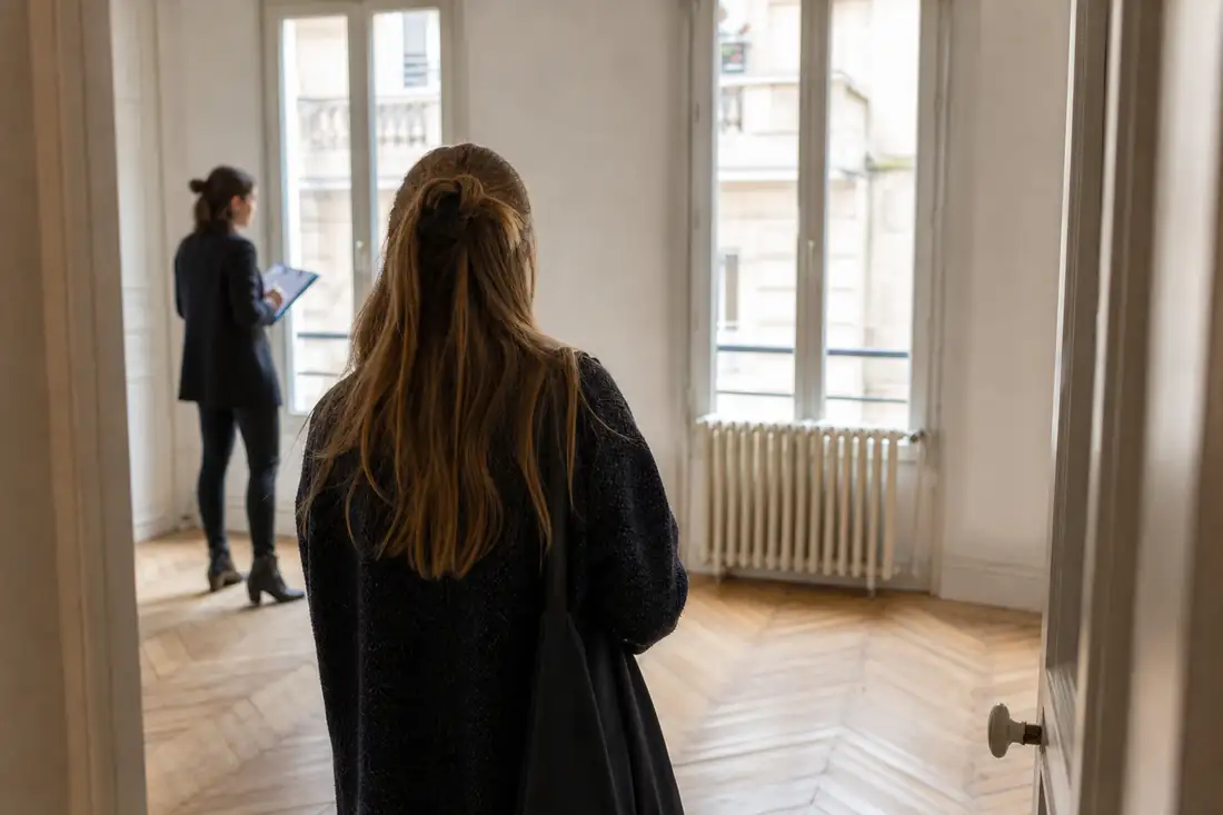 Visite d’un appartement ancien à louer, avec dossier de location et radiateur dans un immeuble urbain français.