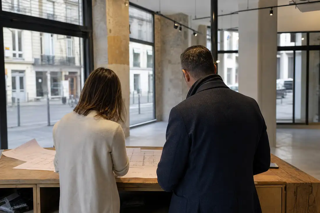 Visite d’un local commercial vacant avant la signature d’un bail, avec plans posés sur un comptoir.