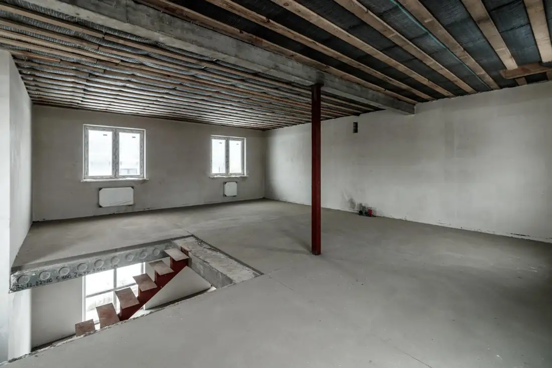 Extension à ossature bois en cours près d’un sous-sol avec tranchée de fondation et mur étanchéifié.
