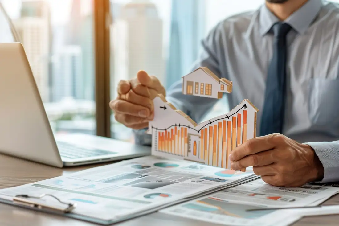 Emprunteur comparant des offres de crédit immobilier et ses mensualités sur une table de cuisine lumineuse.