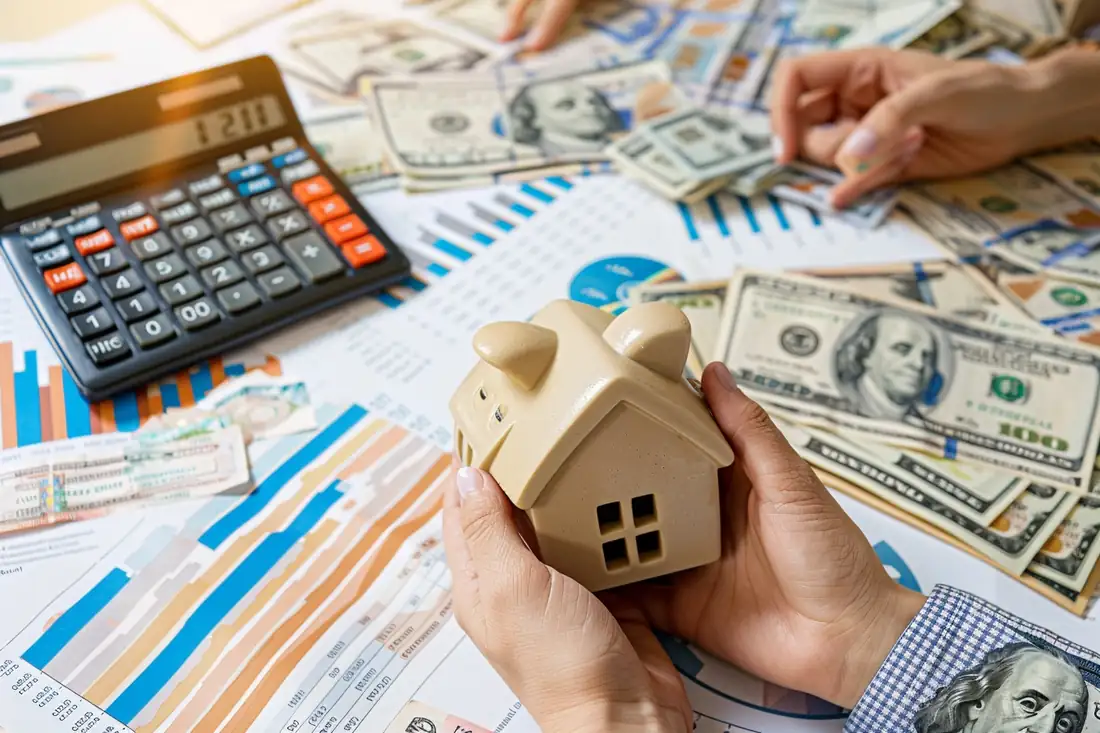 Emprunteur comparant un échéancier de prêt immobilier et une calculatrice lors d’un rendez-vous bancaire.